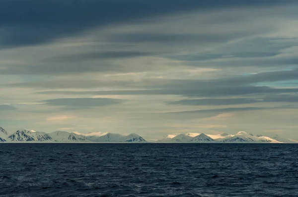 Norveç, Svalbard 'da dağların mavi saatinin panoramik manzarası, kar ve deniz.