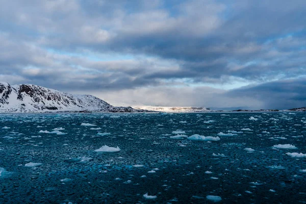 Mar com cubos de gelo derretendo, montanhas nevadas Em Svalbard, Noruega. Aquecimento global. — Fotografia de Stock