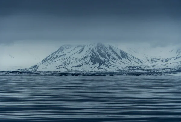 Norveç, Svalbard 'da dağların mavi saatinin panoramik manzarası, kar ve deniz.