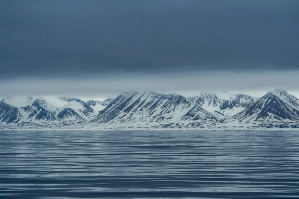 Norveç, Svalbard 'da dağların mavi saatinin panoramik manzarası, kar ve deniz. — Stok fotoğraf