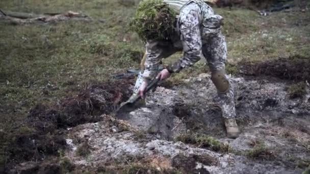 Un soldado cava una trinchera en un bosque de pinos. Preparándose para el ataque. — Vídeo de stock