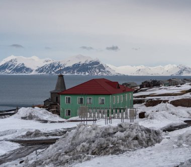 Rus şehri Barentsburg 'un Spitsbergen takımadaları üzerindeki manzarası kışın kutuplarda güneşli havada ve bulutlu gökyüzünde.