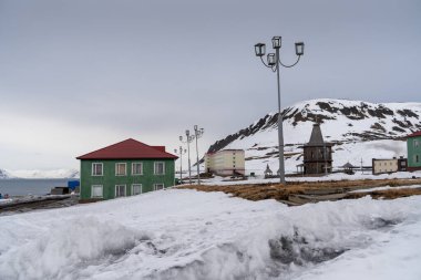 Rus şehri Barentsburg 'un Spitsbergen takımadaları üzerindeki manzarası kışın kutuplarda güneşli havada ve bulutlu gökyüzünde.