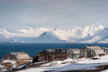 Rus şehri Barentsburg 'un Spitsbergen takımadaları üzerindeki manzarası kışın kutuplarda güneşli havada ve bulutlu gökyüzünde.