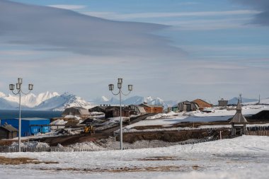 Rus şehri Barentsburg 'un Spitsbergen takımadaları üzerindeki manzarası kışın kutuplarda güneşli havada ve bulutlu gökyüzünde.
