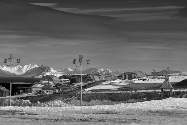 Rusya 'nın Spitsbergen takımadaları üzerindeki Barentsburg şehrinin kışın güneşli havada ve bulutlu havada manzarası. Siyah beyaz fotoğraf
