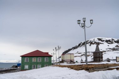 Rus şehri Barentsburg 'un Spitsbergen takımadaları üzerindeki manzarası kışın kutuplarda güneşli havada ve bulutlu gökyüzünde.