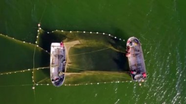 Aerial view to the Baltic sea with the fish traps and fishers loading their Herring catch to their boats. Drone video 4k