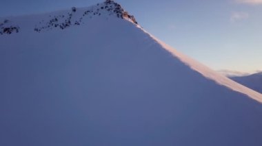 Drone flight near Longyearbyen The sun setting behind the snowy mountains on Svalbard. Flight along the cliff and white snowy mountains High quality 4k footage
