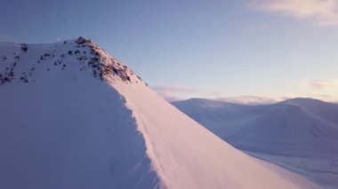 Drone flight near Longyearbyen The sun setting behind the snowy mountains on Svalbard. Flight along the cliff and white snowy mountains High quality 4k footage