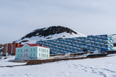 Rus şehri Barentsburg 'un Spitsbergen takımadaları üzerindeki manzarası kışın kutuplarda güneşli havada ve bulutlu gökyüzünde.