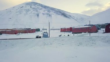 Aerial view of Longyearbyen, Svalbard in winter. With colorful houses, snow-capped mountains, with avalanche protection and old towers. for transporting coal. Drone flight. High quality 4k footage