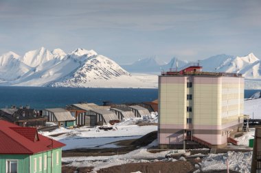 Rus şehri Barentsburg 'un Spitsbergen takımadaları üzerindeki manzarası kışın kutuplarda güneşli havada ve bulutlu gökyüzünde.