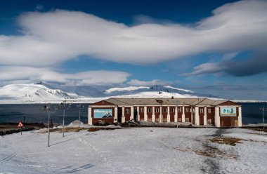 Rus şehri Barentsburg 'un Spitsbergen takımadaları üzerindeki manzarası kışın kutuplarda güneşli havada ve bulutlu gökyüzünde.
