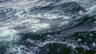 Yelkenli yattan gelen deniz sıçrama dalgalarıyla yaklaşın. Geminin kıç tarafındaki karanlık deniz suyunun görüntüsü, köpüklü ve sıçramalı dalgalar, geminin hareketinden sonra dağılır..