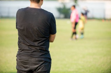 Baba, oğlunun güneşli bir günde bir okul turnuvasındaki futbol maçını seyrediyor. Spor, açık hava etkinliği, yaşam tarzı, mutlu aile ve futbol annesi ve futbolcu baba kavramı..