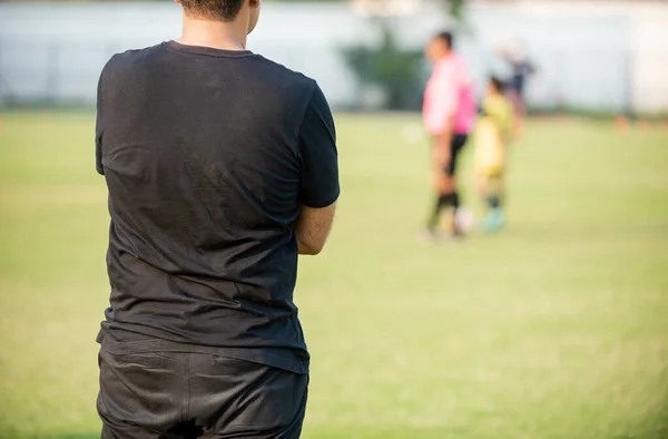 Father Standing Watching His Son Playing Football School Tournament Sideline — стоковое фото