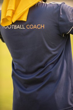 Açık havada ve güneşli bir günde erkek futbol koçu okul turnuvasında takımının maçını seyrediyor. Spor, aktif yaşam tarzı, mutlu aktivite ve koçluk konsepti.