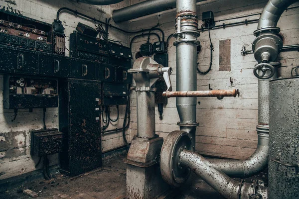 Eski sanayi binasının yüzeyinde vanaları olan metal boru hatları..