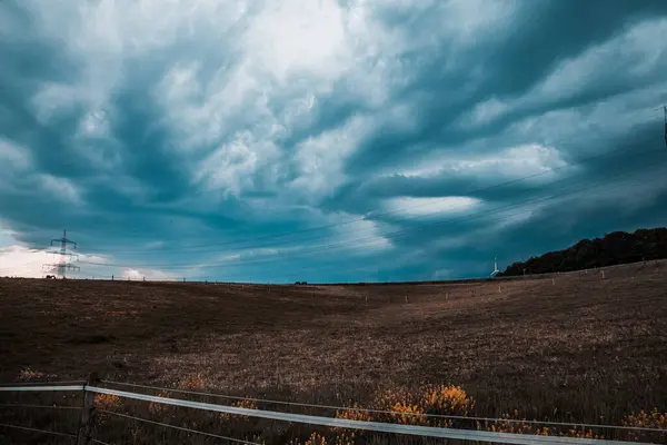 Ağaçlarla dolu bir tarlası ve bulutlu bir gökyüzü olan güzel bir manzara.