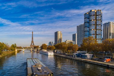 Güneşli sonbahar gününde Eyfel Kulesi ve gökdelenleri olan Seine Nehri 'ndeki tekneler