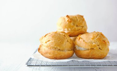 Beyaz ahşap arka planda metal ızgarada ev yapımı profiteroller..