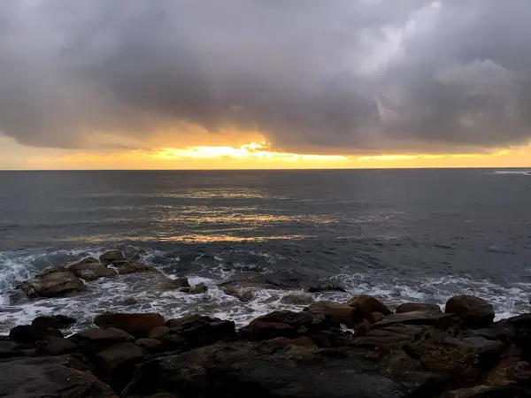 Okyanus üzerinde fırtınalı gün doğumu, kayalık kıyı şeridi