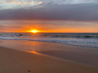 Sahile vuran gün doğumu - bulutlar arasından ışınlar
