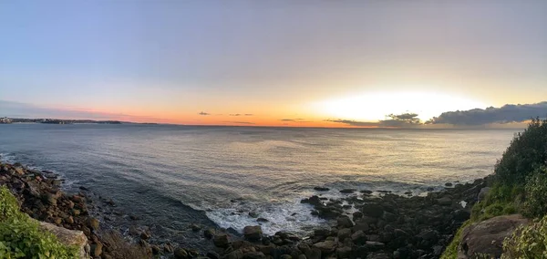 Panografik okyanus gündoğumu, küçük dalgalar çarpıyor