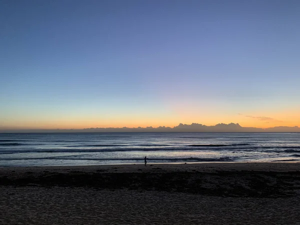 Okyanusun üzerinde az bulutla altın gün doğumu, sahil yürüyüşçüsü