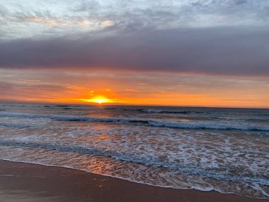 Okyanusun üzerinde koyu turuncu gün doğumu
