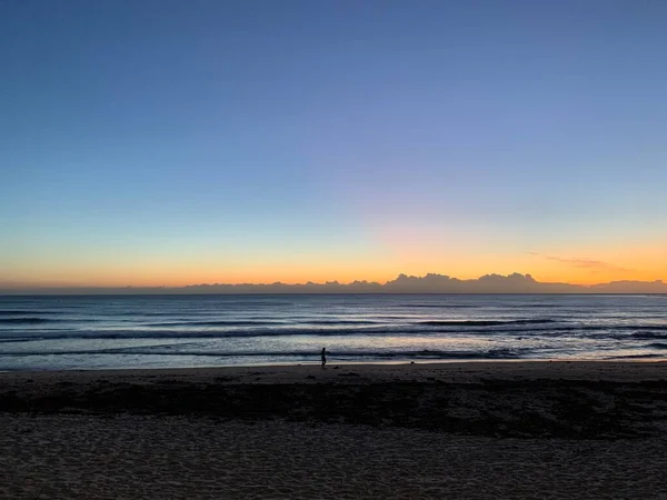 Yalnız yürüyenle okyanusun üzerinde çarpıcı bir gün doğumu.