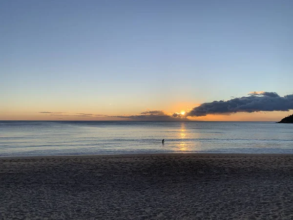 Suda yalnız sörfçülerle durgun okyanusun üzerinde gün doğumu