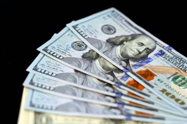 Amerikan para banknotunun seçici odak noktası siyah bir arka planda, 100 Amerikan dolarının yüz dolarlık banknotunun ters tarafında Başkan Benjamin Franklin 'in portresi var.