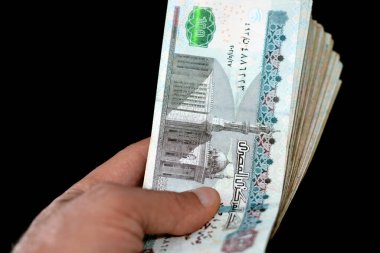 Adam elinde 100 LE 100 Mısırlı banknot destesi, harcama, para verme ve kullanma, ödeme ve satın alma siyah arka planda izole banknotlar kullanarak