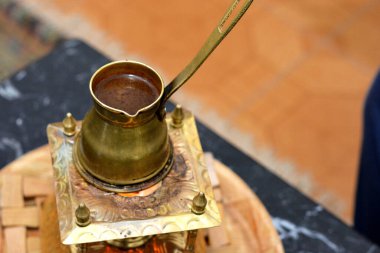 Türk kahvesi, bakır el yapımı Türk kahve makinesinde kahvaltıyla içmek, rahatlamak ve mola vermek için hazırlanıyor. Sabah rutini, bulanık arka plan.