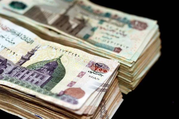 200埃及镑和100埃及镑钞票的正面堆叠成堆 200镑印着卡尼湾清真寺的形象 100镑印着苏丹哈桑清真寺被隔离在黑暗中的形象 — 图库照片