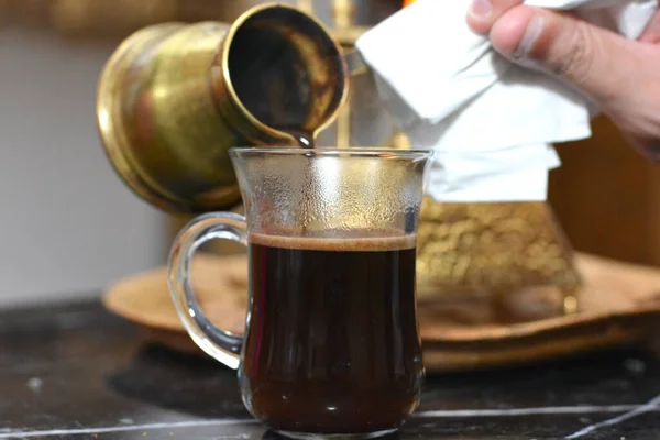 手作りのトルコ式コーヒースピリットバーナーの炎の上に作られた銅製の鍋からガラスマグカップにトルコのコーヒーを入れて リラックスして休憩時間の概念 朝のルーチンで飲む — ストック写真