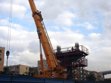Mısır 'ın inşaat sahasında çelik ve beton dairesel kolonlar, yapı iskelesi ve bir vinç ile tek hat demiryolu taşıma sistemi üzerinde yükseltilmiş iki ray var.