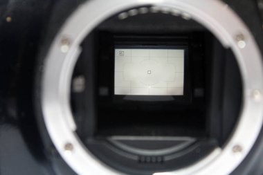 Ayna ve kamera sensörünü gösteren gövde kapağı olmayan bir DSR dijital kamerasının ön görüntüsüne seçici bir odak, iç kısımları gösteren eski bir dslr dijital fotoğrafçılık ve video kamera çözülmüş