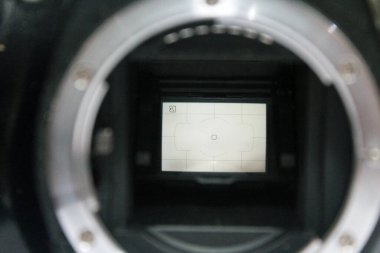 Ayna ve kamera sensörünü gösteren gövde kapağı olmayan bir DSR dijital kamerasının ön görüntüsüne seçici bir odak, iç kısımları gösteren eski bir dslr dijital fotoğrafçılık ve video kamera çözülmüş