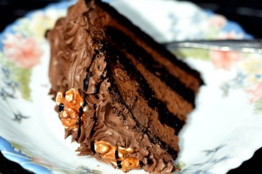 Cevizli ve soslu lezzetli bir çikolatalı pasta çikolata soslu ve kremalı çikolata pastası çatallı bulanık çikolatalı kek dilimi.