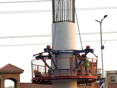 Giza, Mısır, 9 Aralık 2021: Mısır inşaat sahasında işçiler tek raylı taşıma sisteminde çelik parçaları bir vinç tarafından Giza demiryolunun çelik ve beton sütununa monte edip monte ediyorlar.