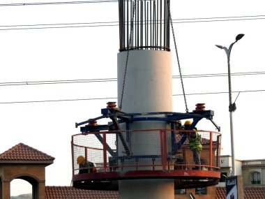 Giza, Mısır, 9 Aralık 2021: Mısır inşaat sahasında işçiler tek raylı taşıma sisteminde çelik parçaları bir vinç tarafından Giza demiryolunun çelik ve beton sütununa monte edip monte ediyorlar.