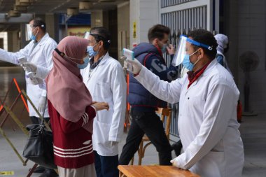 Bina girişinden önce katı önlemler, yüz maskeleri, el jelleri, temassız kızılötesi termometre ile sıcaklık taraması ve koronavirüs küresel kriz salgınının ortasında covid-19 yayılmasını önlemeye çalışan sosyal mesafeler