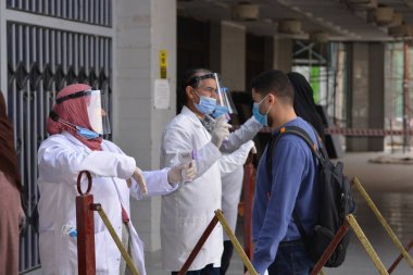 Bina girişinden önce katı önlemler, yüz maskeleri, el jelleri, temassız kızılötesi termometre ile sıcaklık taraması ve koronavirüs küresel kriz salgınının ortasında covid-19 yayılmasını önlemeye çalışan sosyal mesafeler