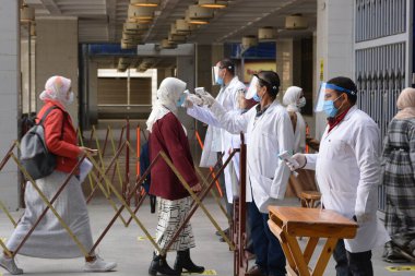 Bina girişinden önce katı önlemler, yüz maskeleri, el jelleri, temassız kızılötesi termometre ile sıcaklık taraması ve koronavirüs küresel kriz salgınının ortasında covid-19 yayılmasını önlemeye çalışan sosyal mesafeler