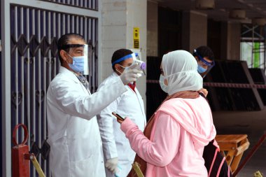 Bina girişinden önce katı önlemler, yüz maskeleri, el jelleri, temassız kızılötesi termometre ile sıcaklık taraması ve koronavirüs küresel kriz salgınının ortasında covid-19 yayılmasını önlemeye çalışan sosyal mesafeler