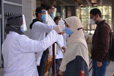 Mısır 'da sıkı koronavirüs önlemleri altında üniversite binasına giriş, covid-19 virüsünün yayılmasına karşı ihtiyati tedbirler, temas olmayan kızılötesi termometre, sosyal uzaklık ve yüz maskeleri takarak sıcaklığı kontrol etme