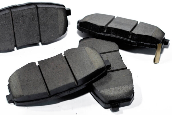 селективное фокусирование набора новых неиспользуемых автоматических тормозных колодок для автомобиля, изолированного на белом, автомобильном обслуживании и техническом обслуживании, запасных частей для автомобиля, стальных опорных плит с фрикционным материалом